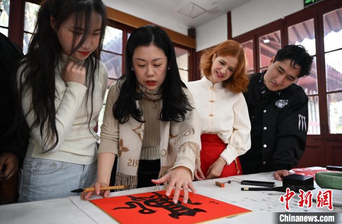 1月20日，西泠印社社員李硯（左二）為外籍留學生講述蛇年福字貼創作靈感。當日，來自巴西、馬來西亞、加納、哈薩克斯坦的外籍留學生在浙江杭州西泠印社體驗福貼、春聯和篆刻，感受古老的中國傳統文化。中新社記者 王剛 攝