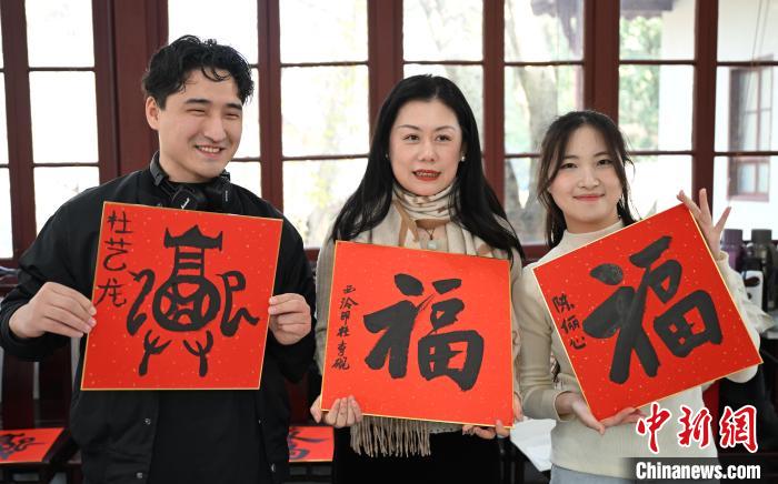 1月20日，外籍留學生和西泠印社社員李硯(中)展示各自創作的福貼。當日，來自巴西、馬來西亞、加納、哈薩克斯坦的外籍留學生在浙江杭州西泠印社體驗福貼、春聯和篆刻，感受古老的中國傳統文化。中新社記者 王剛 攝