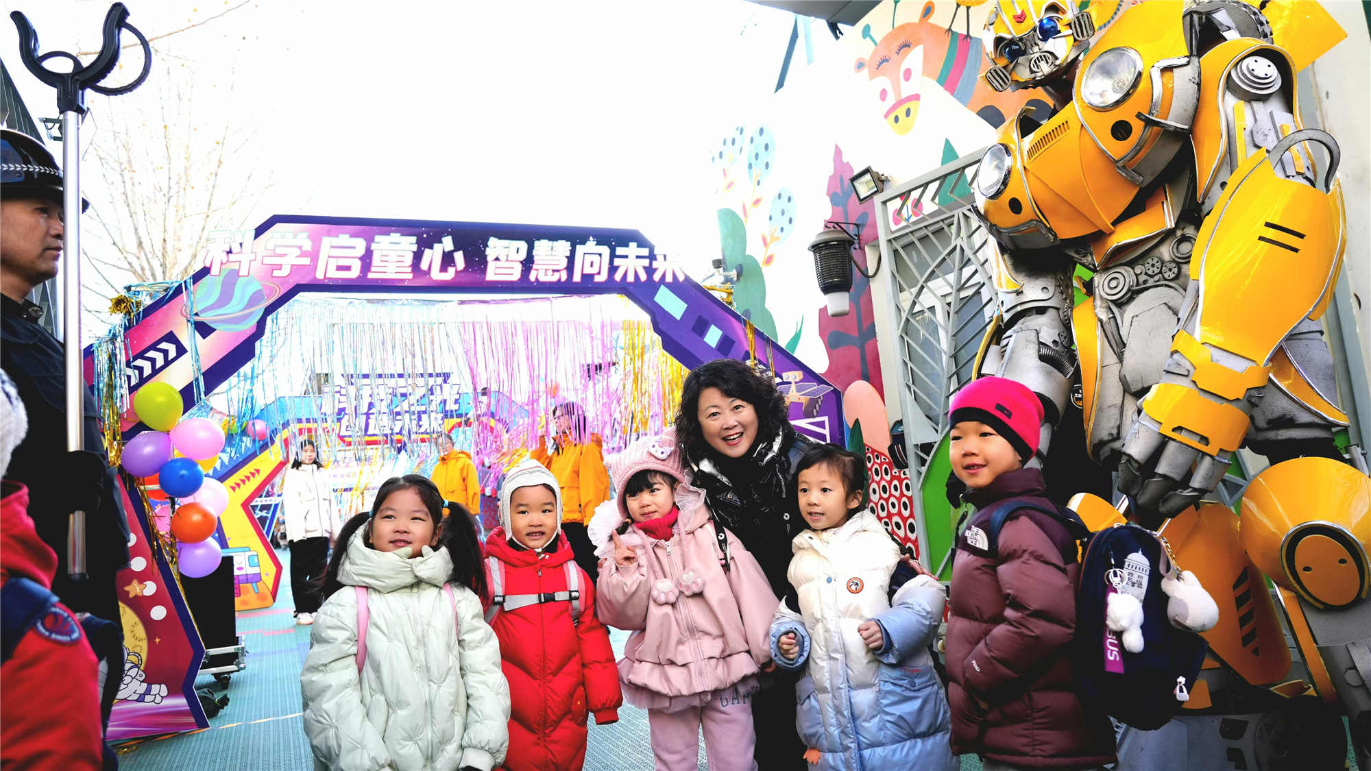 北京市東城區欣苑幼兒園的小朋友們在老師與機器人共同迎接下入園。幼兒園供圖