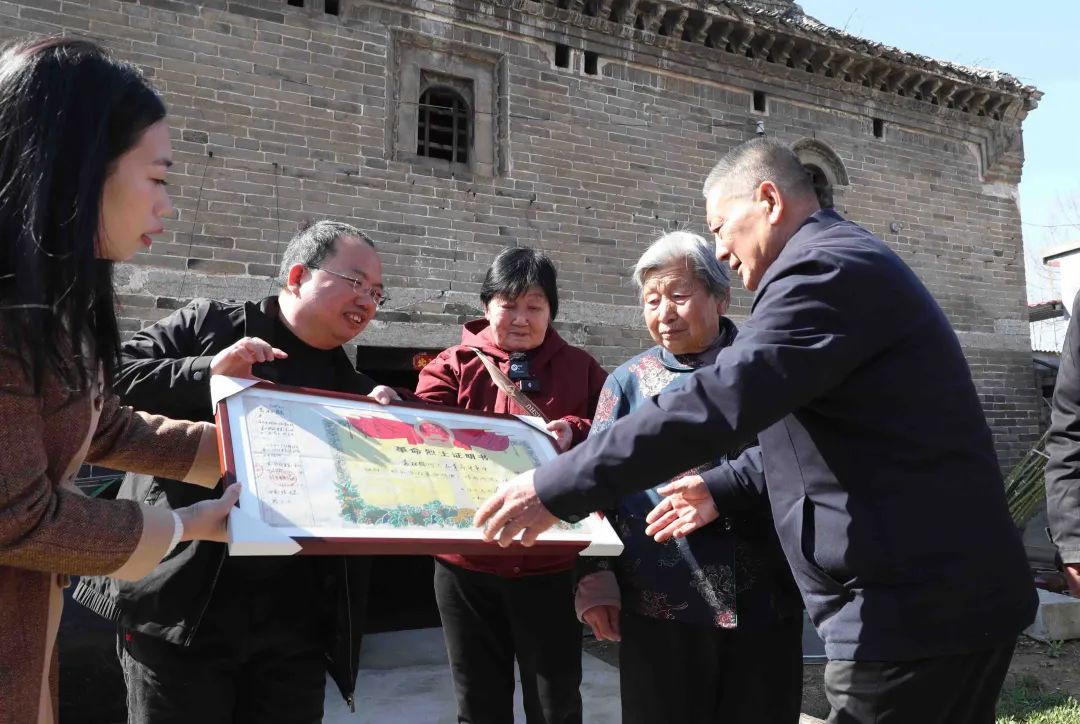河南省許昌市建安區袁莊，曹明（左二）將修復好的革命烈士證明書交到袁松鶴烈士的家屬手中。