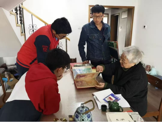 2019年，岳同給來家看望的志愿者們展示收藏的剪紙、中國畫作品。中國人民大學供圖