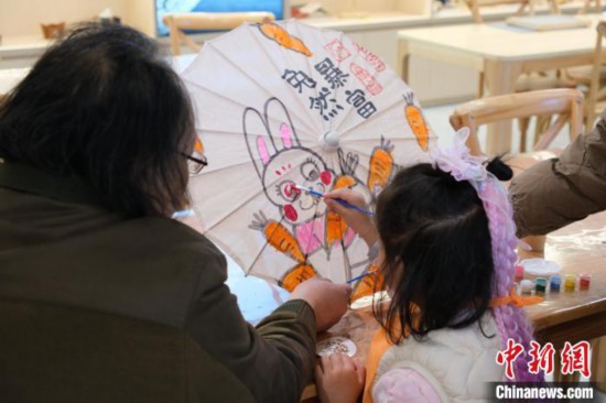 2月7日，浙江杭州，小朋友在綢布傘上體驗彩繪。春節期間，浙江省非物質文化遺產館成為家庭出游的熱門之選，民眾在傳統技藝體驗中感受年味。中新社記者 曹丹 攝