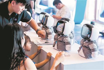 在第三屆軟件創新發展大會上，一名小女孩與陪伴機器人互動。中新社記者 張暢攝