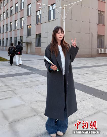 劉沫含在宿舍前拍照，她身著“雙十一”花200多元買的風衣。 受訪者供圖